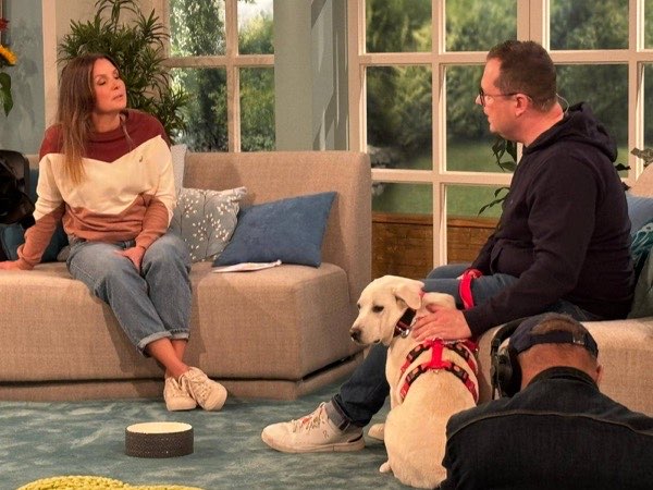 Dr. Florian Wuchert im Gespräch mit Moderatorin Simone Sombecki, neben ihm liegt ein heller Labrador